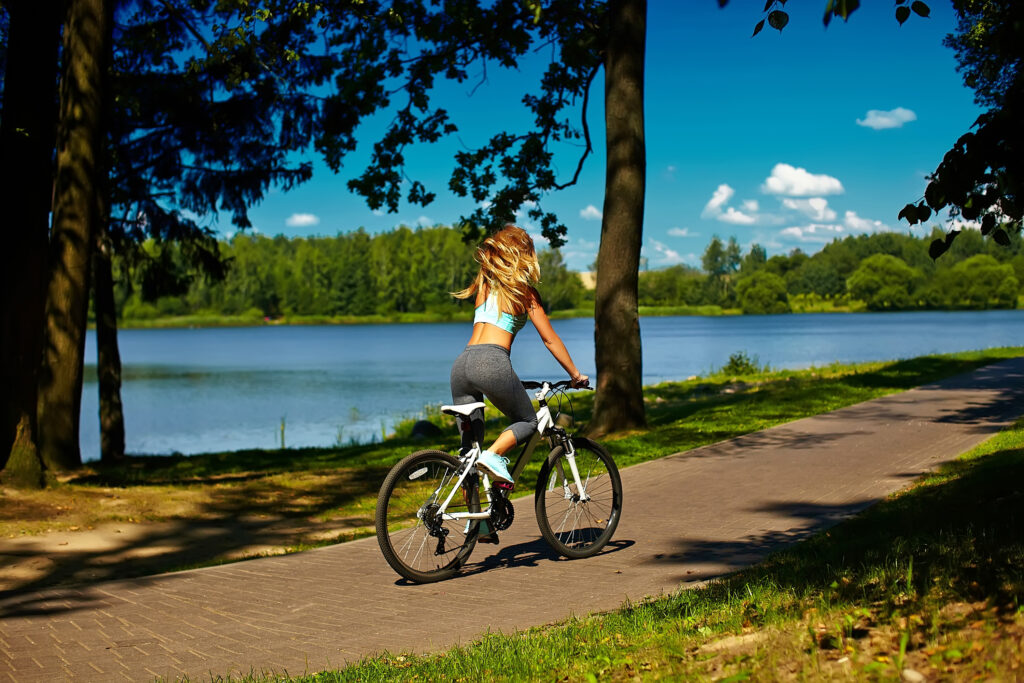 bladynka jedzie na rowerze droga rowerową nad brzegiem jeziora porajskiego